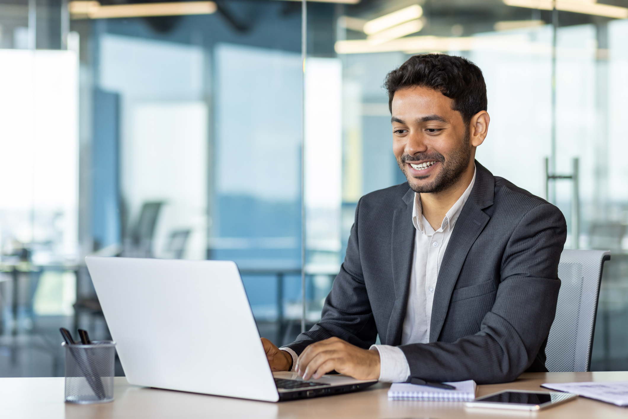 A smiling man using his laptop in an office setting