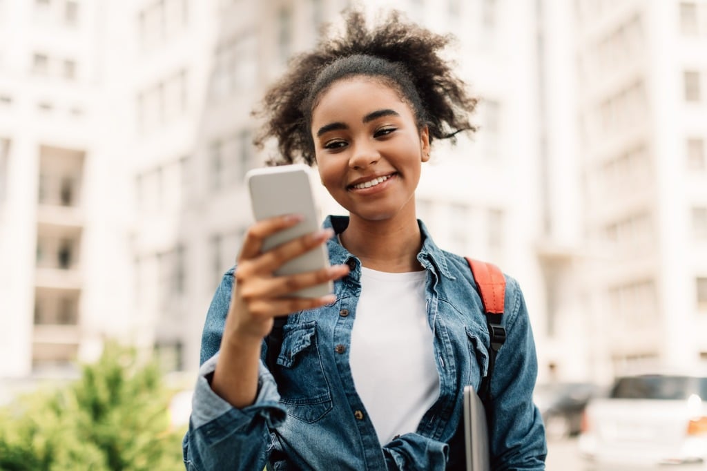 cheerful-african-american-student-girl-using-mobile-phone-standing-outside.jpg_s=1024x1024&w=is&k=20&c=D_SPIomXUrvlF3pjbEFbPOO4wr-Qv7lA7yYp_0_jHs4=