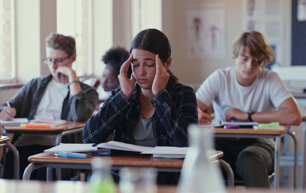 Stressed student at her desk holding her head